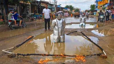 A man dressed as astronauts stands in a waterlogged road crater to highlight civic issues and protest against waterlogging in the Jhotwara area, in Jaipur (PTI photo) 'Astronauts' land on road craters: Over 100 Jaipur residents stage unique protest against potholes